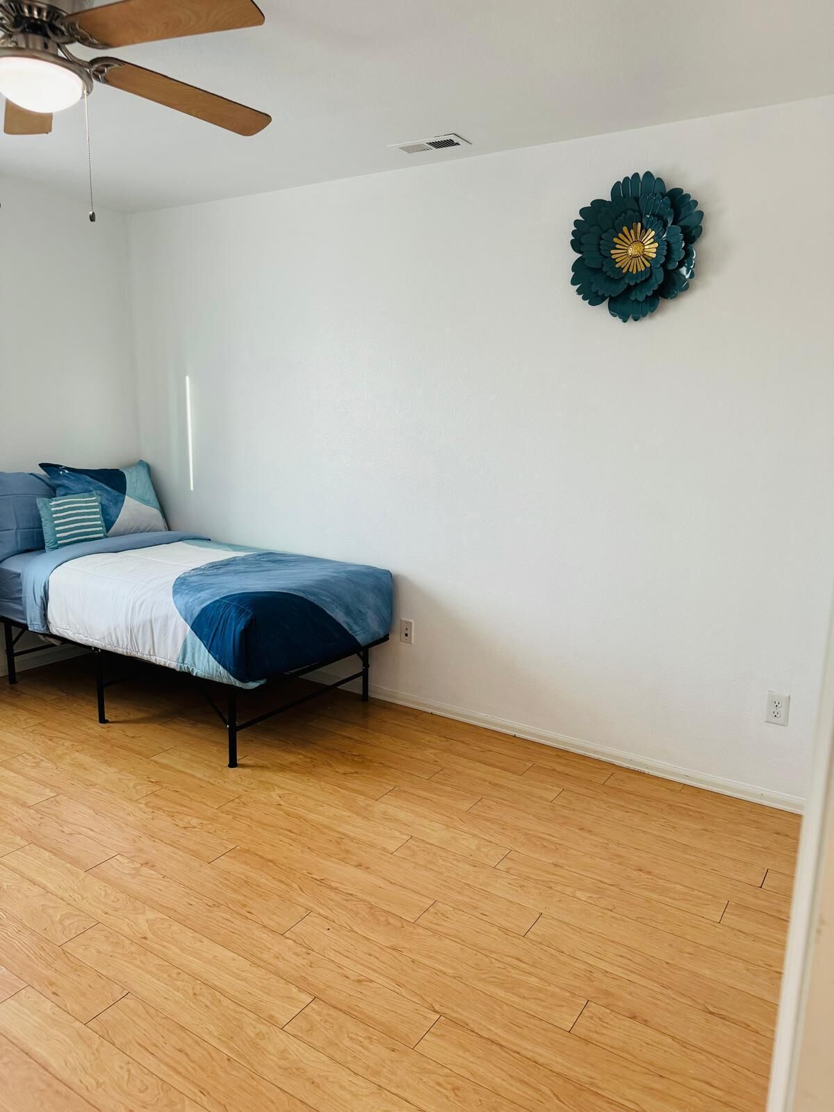 Un dormitorio con cama, ventilador de techo y un adorno en la pared.