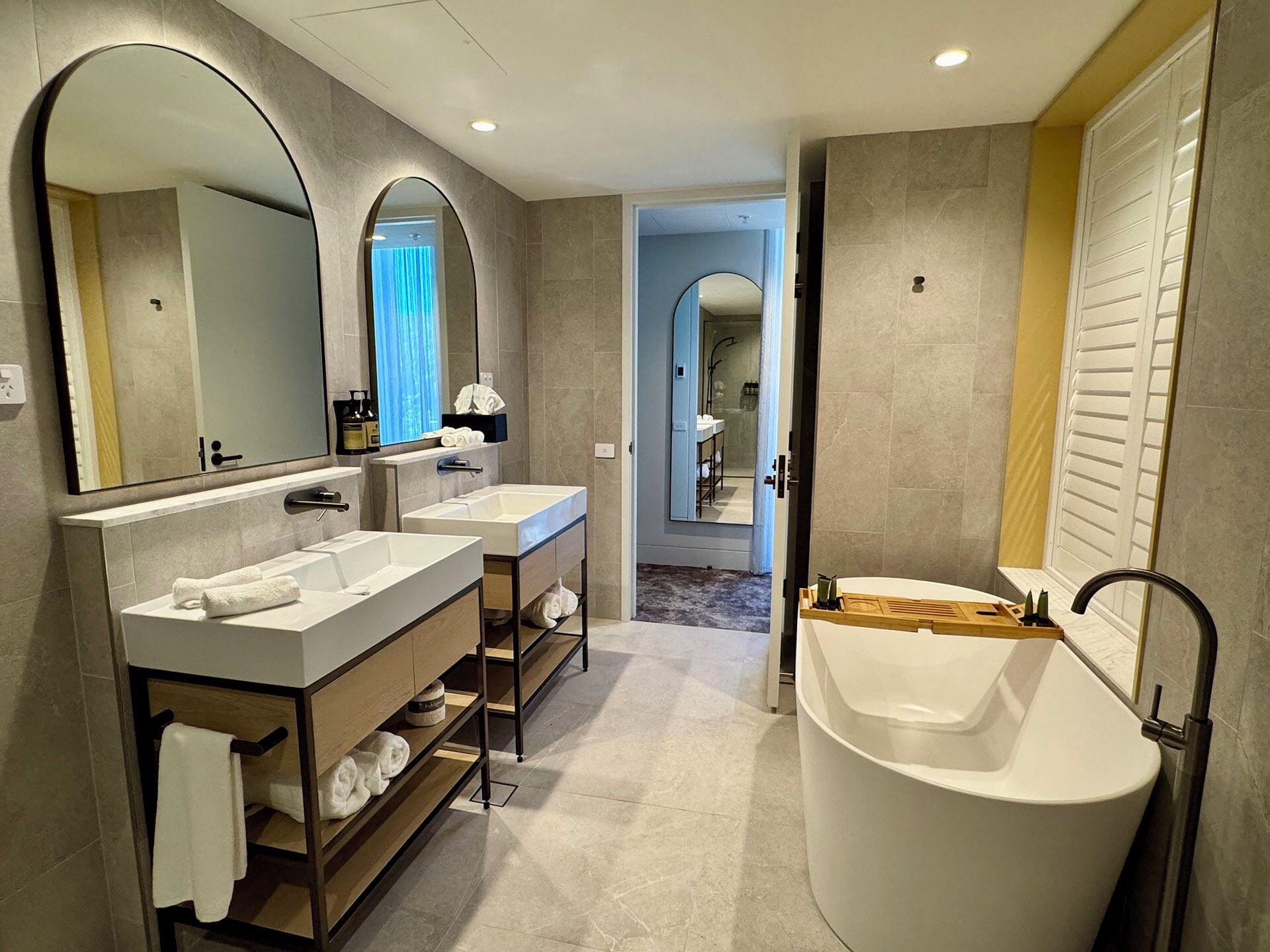 A modern bathroom with two sinks, a large bathtub, and a mirror.