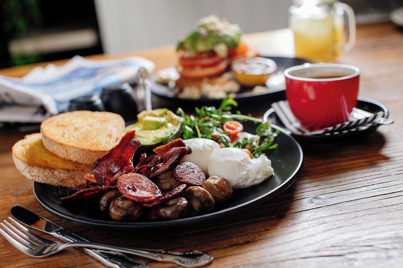 Un plato de desayuno con huevos, tocino, champiñones, tostadas y una ensalada.