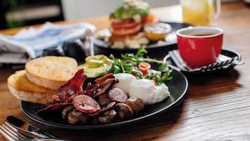 Un plato de desayuno con huevos, tocino, champiñones, tostadas y una ensalada.