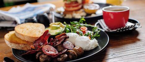 Un plato de desayuno con huevos, tocino, champiñones, tostadas y una ensalada.