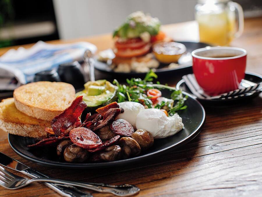 Ein Frühstücksteller mit Eiern, Speck, Pilzen, Toast und Salat.