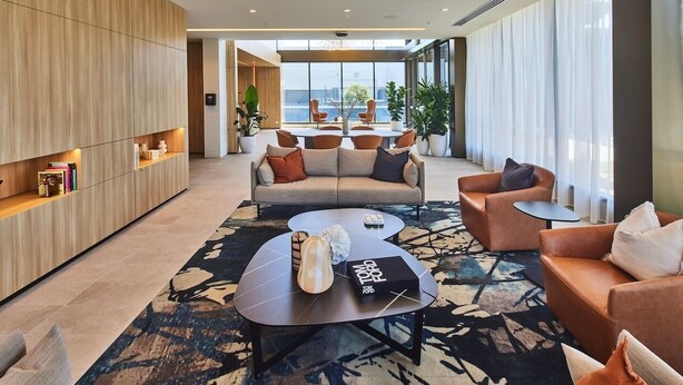 Uma sala de estar moderna com um sofá, poltronas, uma mesa de centro e uma estante.