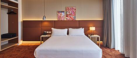 A hotel room with a large bed, two bedside tables, a wardrobe, and a headboard with artwork.