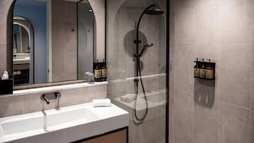 A modern bathroom with a white sink, a large mirror, and a glass-enclosed shower area.