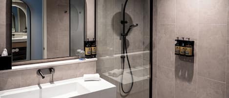 A modern bathroom with a white sink, a large mirror, and a glass-enclosed shower area.