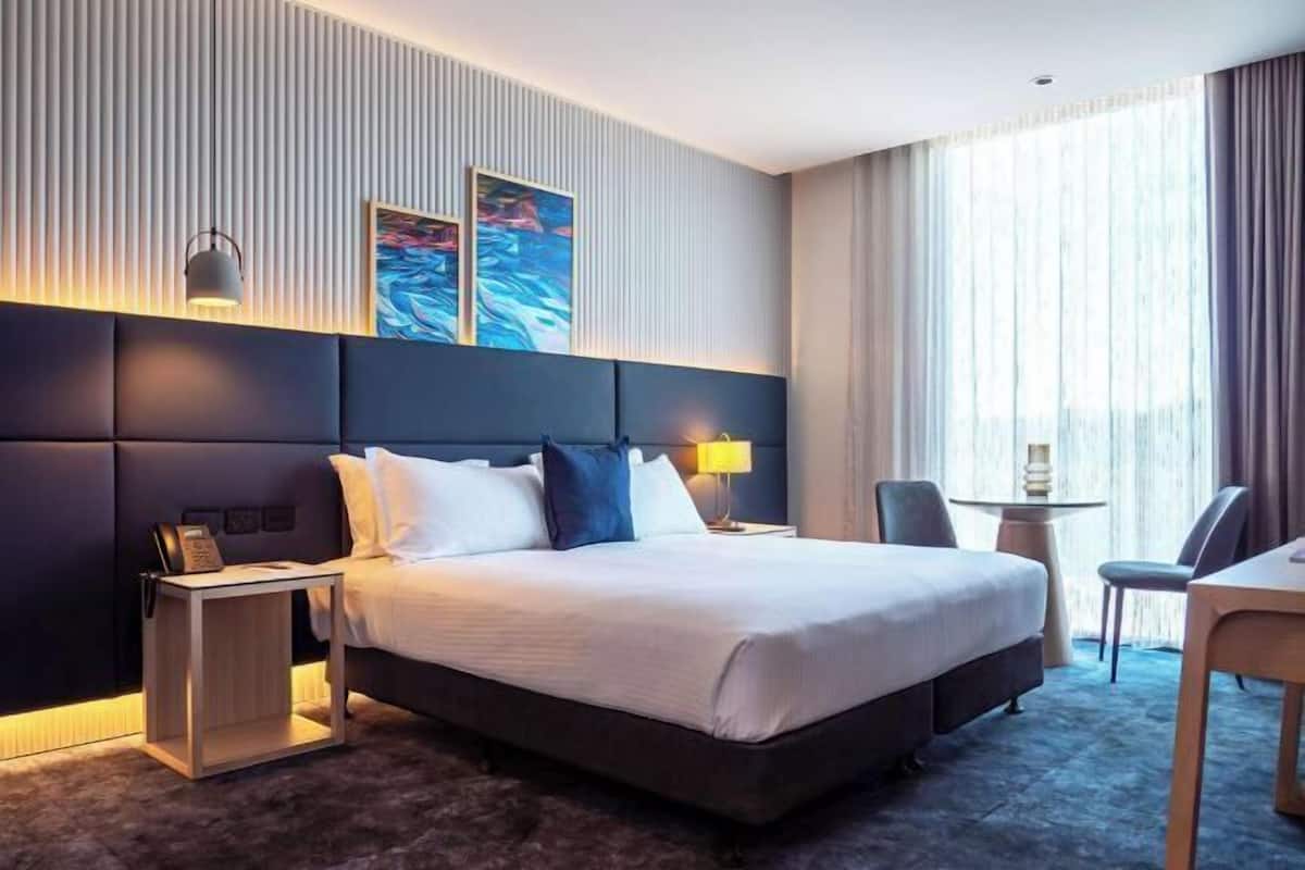 A hotel room with a large bed, bedside tables, a desk, and a chair.