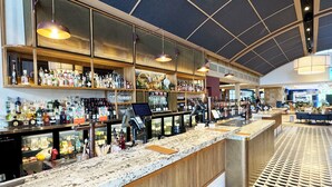 Uma área de bar com bancada de mármore, prateleiras cheias de garrafas de bebidas e piso estampado.