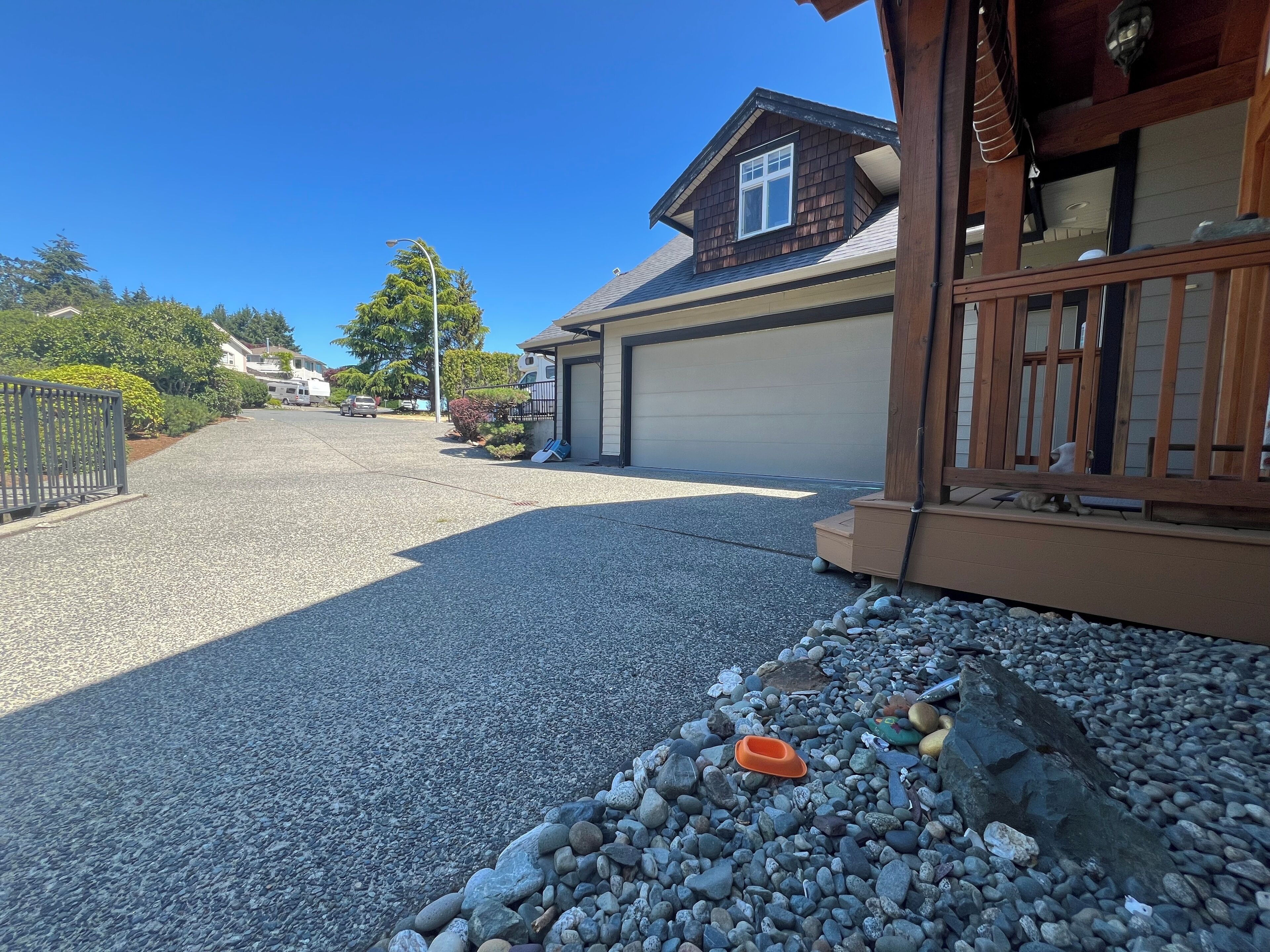 A residential driveway with a gravel surface, a wooden fence, and a garage.