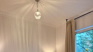 Habitación de hotel con una cama grande, dos almohadas, una lámpara de noche y vistas a árboles a través de la ventana.