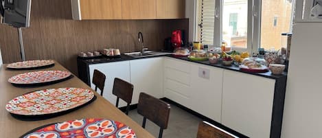 A modern kitchen with a wooden cabinet, a sink, and a dining area with chairs.