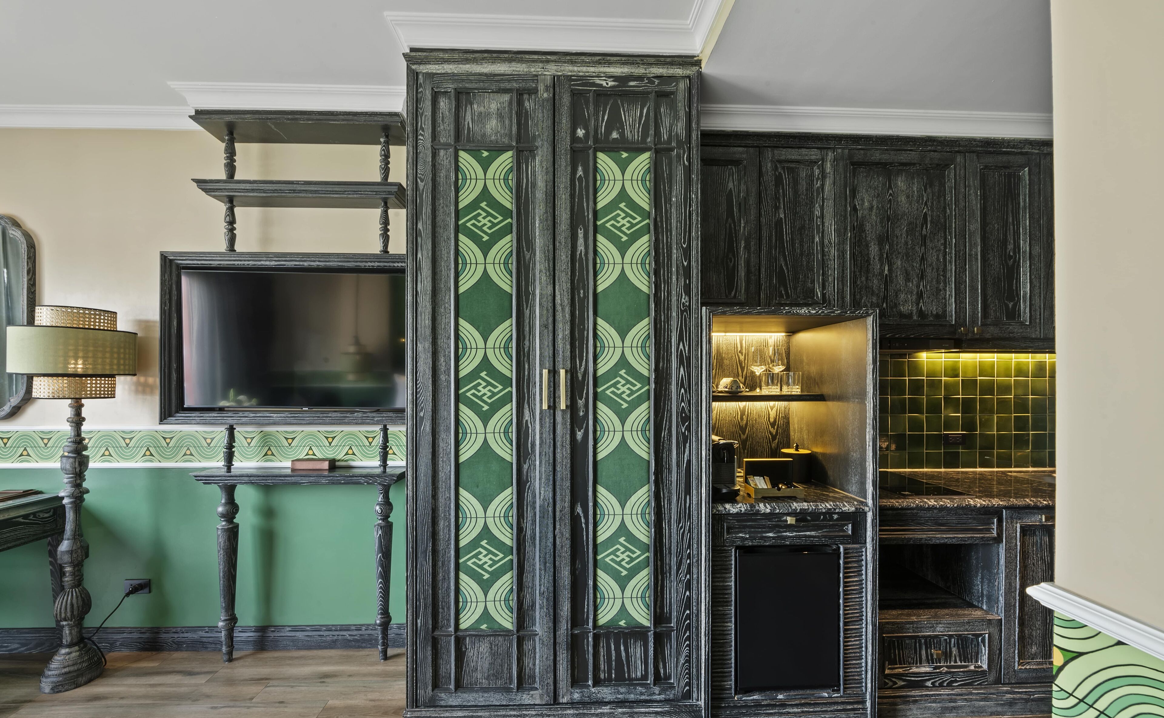 Una cocina con gabinetes de madera oscura, un salpicadero con estampado verde y una estufa empotrada.