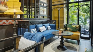 Une pièce avec un canapé bleu, une table ronde et un fauteuil vert à motifs floraux.