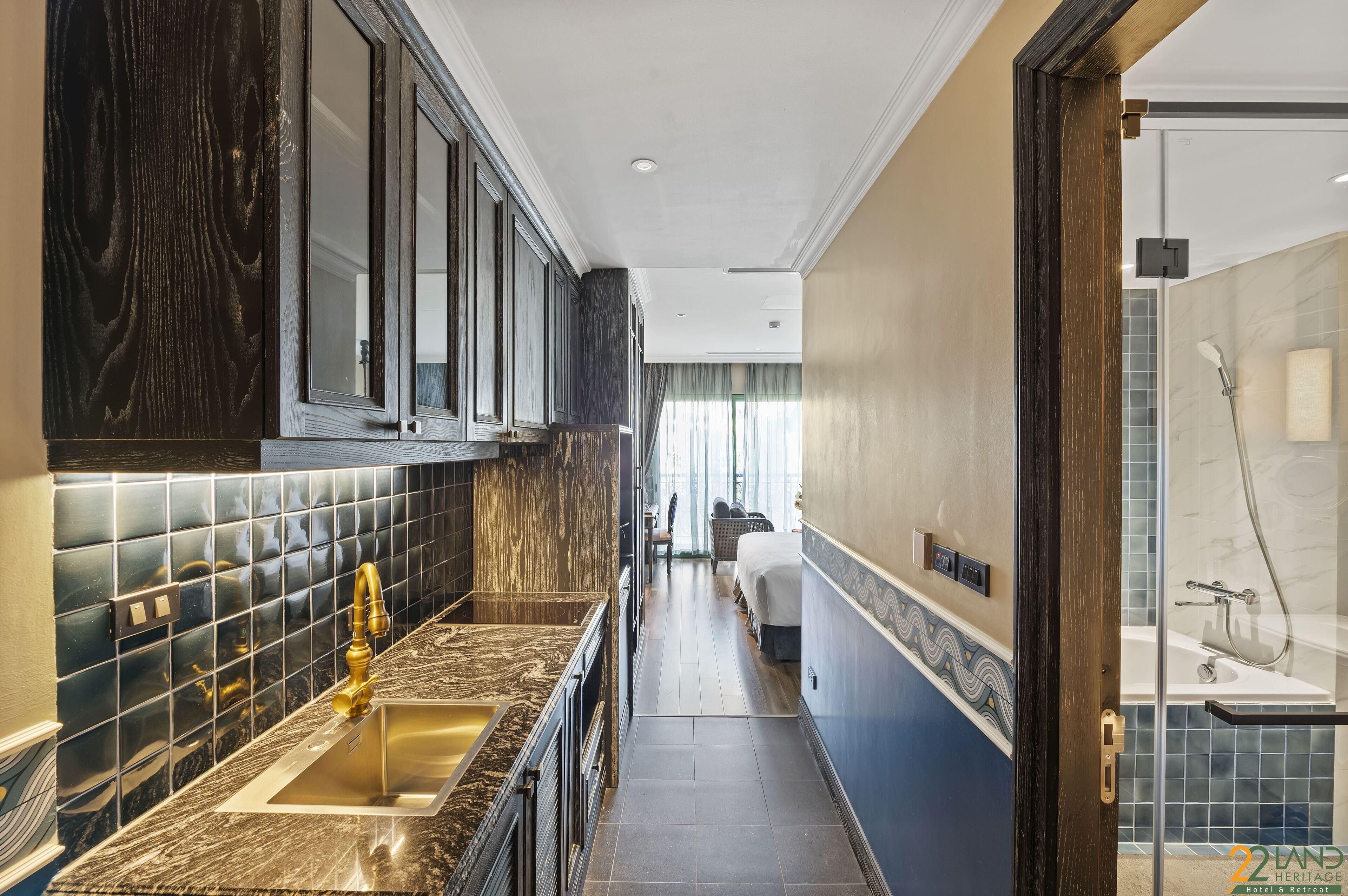 A modern hotel bathroom with a glass shower enclosure, a sink with a gold faucet, and a vanity with a dark wood cabinet.