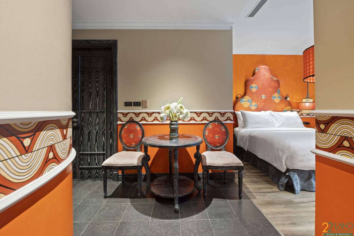 A hotel room with a bed, a round table with chairs, and a decorative wall.
