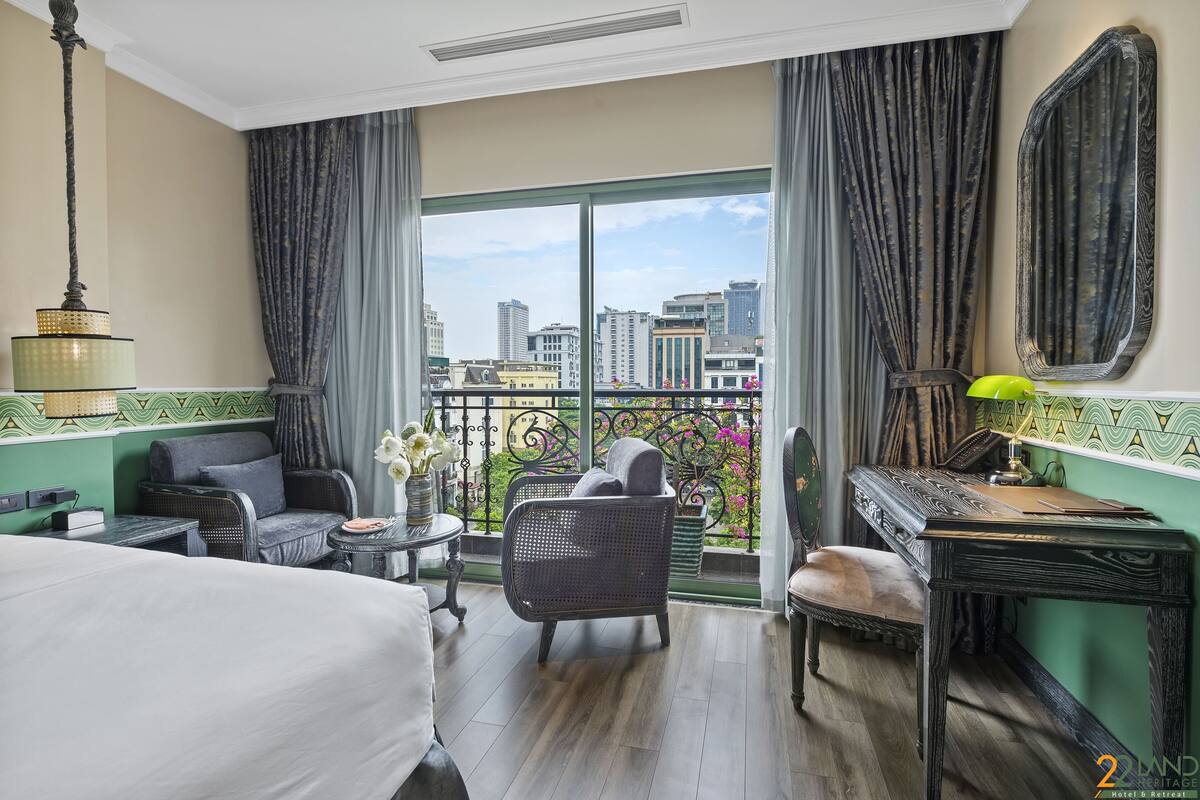 A hotel room with a balcony, a bed, a desk, and a chair.