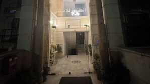 Sisäänkäynti, jossa on kaareva oviaukko, ruukkukasveja ja arabialaisella tekstillä varustettu kyltti.