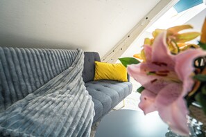 Ein graues Sofa mit einem gelben Kissen und einer grauen Decke.