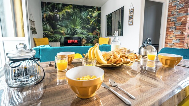 A breakfast setup with a coffee maker, bowls, and a plate of croissants and bananas on a wooden table. - An enchanting townhouse, a unique experience! (Nozay)