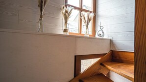 A wooden staircase with a window above, leading to a landing. There are three vases with dried plants on the window sill. - An enchanting townhouse, a unique experience! (Nozay)