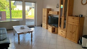 Una sala de estar con un mueble de madera, un televisor y una mesa.