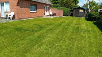 A well-maintained lawn, a brick house, and a small shed.