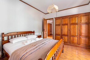 Une chambre à coucher avec un lit en bois, une armoire et un sol carrelé.