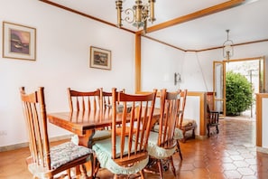 Un coin repas avec une table et des chaises en bois, un lustre et des tableaux encadrés accrochés aux murs.