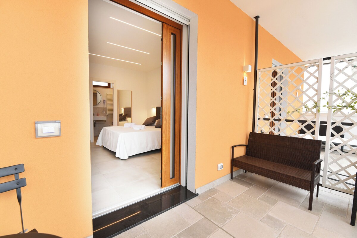 Ein Hotelzimmer mit einem Bett, einer Sitzbank und einer Schiebetür, die auf einen Balkon führt.