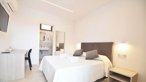 Quarto com cama, mesa de cabeceira e escrivaninha com cadeira.