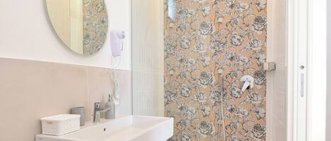 A modern bathroom with a shower, a sink, and a mirror.