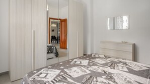 A bedroom with a bed, a dresser, a mirror, and a wardrobe. - GuestHost - Stylish City Living in Central Catania (Catania)