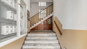 A marble staircase with a wooden handrail and glass doors on the left. - GuestHost - Stylish City Living in Central Catania (Catania)
