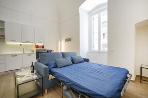 Une chambre à coucher de taille réduite, comprenant un lit, une petite table et un coin cuisine.