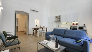 Ein modernes Wohnzimmer mit einer Couch, einem Essbereich und einer Küche im Hintergrund.
