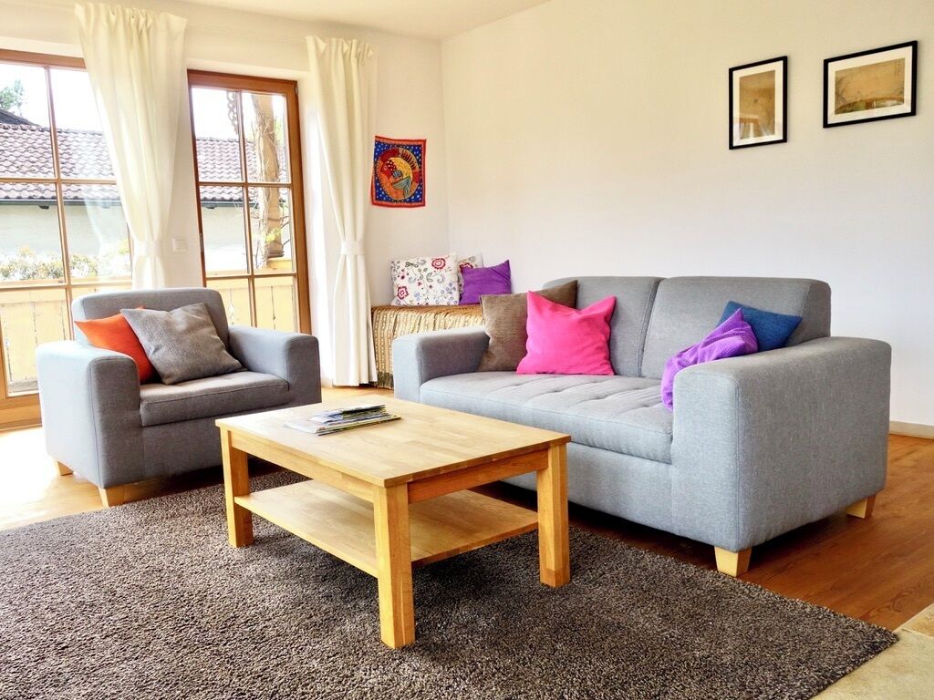 Una sala de estar con dos sofás grises, una mesa de centro de madera y una alfombra estampada.