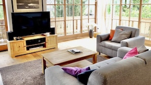Ein Wohnzimmer mit Fernseher, grauem Sofa und Couchtisch aus Holz.