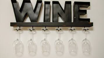 Ein an der Wand befestigtes Schild mit dem Wort 'WINE' und darunter sechs hängende Weingläser.