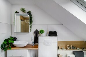 A modern bathroom with a white sink, a mirror, a towel rack, and a wooden vanity.