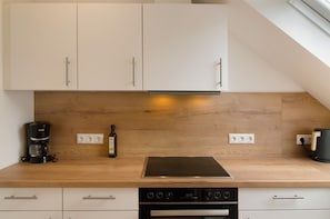 A kitchen with white cabinets, a wooden countertop, a built-in stove, and a coffee maker.