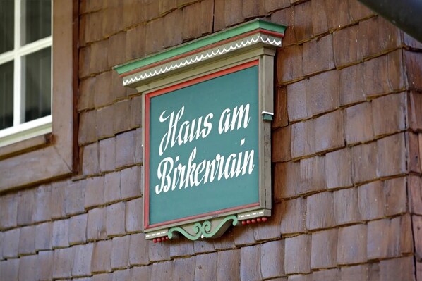 Un letrero con el texto 'Haus am Birkenhain' en una pared de ladrillo.
