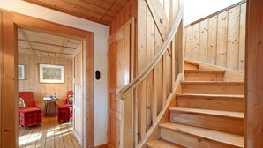 Una escalera de madera que lleva a una habitación con piso de madera y una puerta.