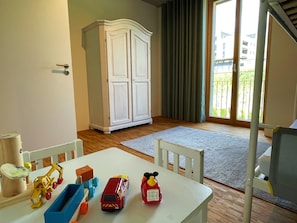 A room with a white table, toys, a white cabinet, and a view through a glass door.