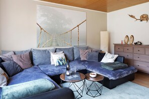 Ein modernes Wohnzimmer mit einer Eckcouch, einem Couchtisch und einem großen Gemälde einer Brücke.