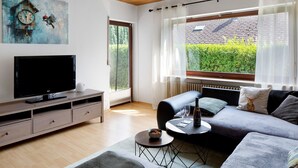 Een moderne woonkamer met een flatscreen televisie, bank en een eettafel.