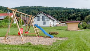 A playground with swings and a slide, surrounded by a grassy area with houses in the background. - Holiday Home 'Bollenhut' with Private Terrace, Wi-Fi and Air Conditioning (Oberkirch)