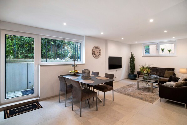 Una sala de estar moderna con comedor, ventanas amplias, televisor de pantalla plana y sofá.