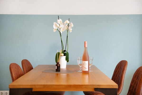 A wooden table with a bottle of Secco wine, two glasses, and a vase with white flowers.