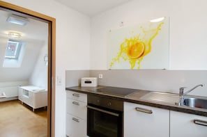 A kitchen with a sink, oven, and a white cabinet.