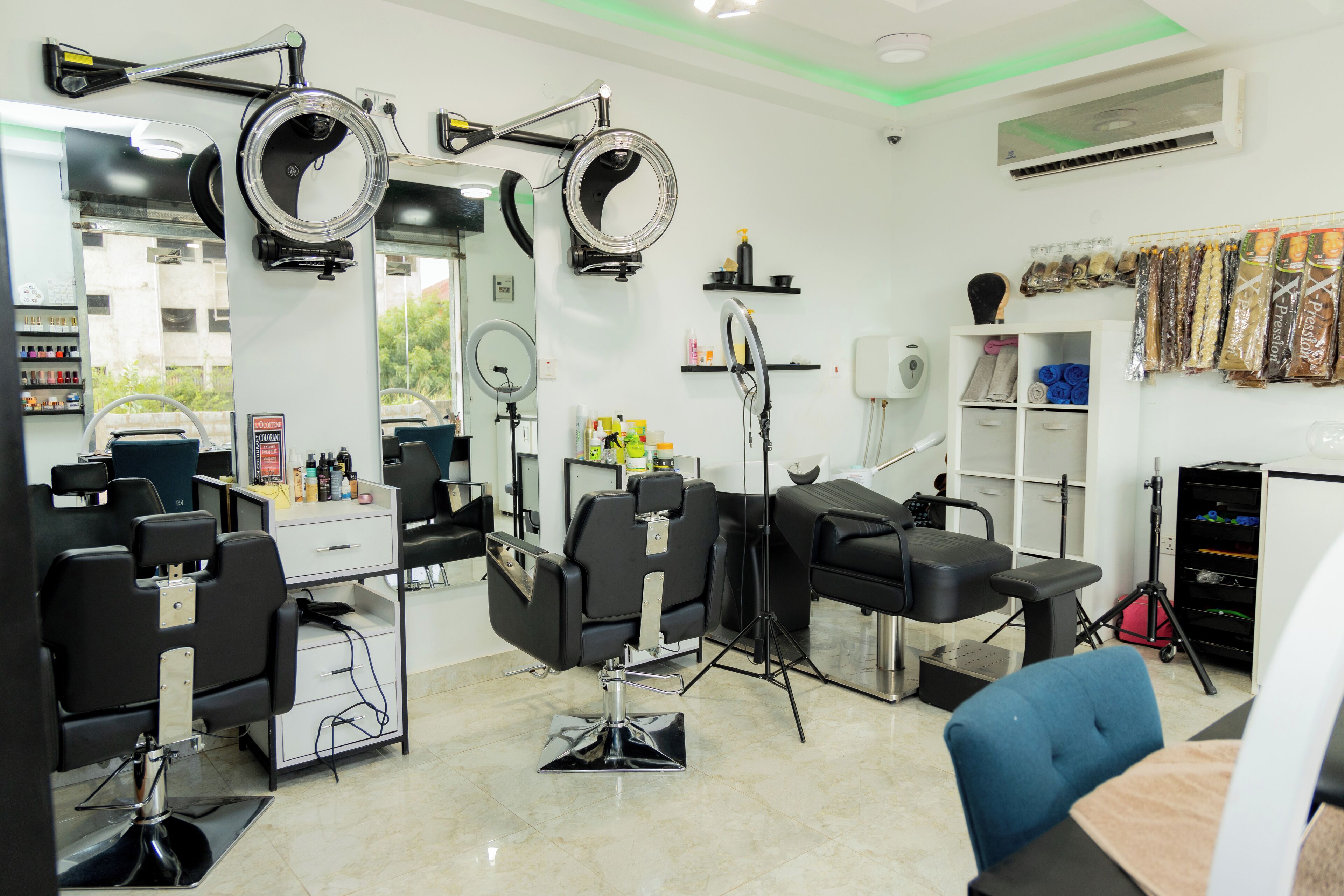 A salon with multiple hairdressing stations, mirrors, and shelves with hair products.
